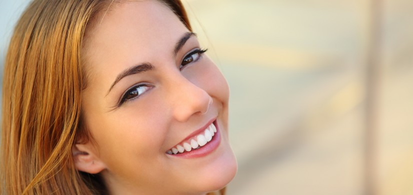 Beautiful woman with a perfect white smile and smooth skin with an unfocused background